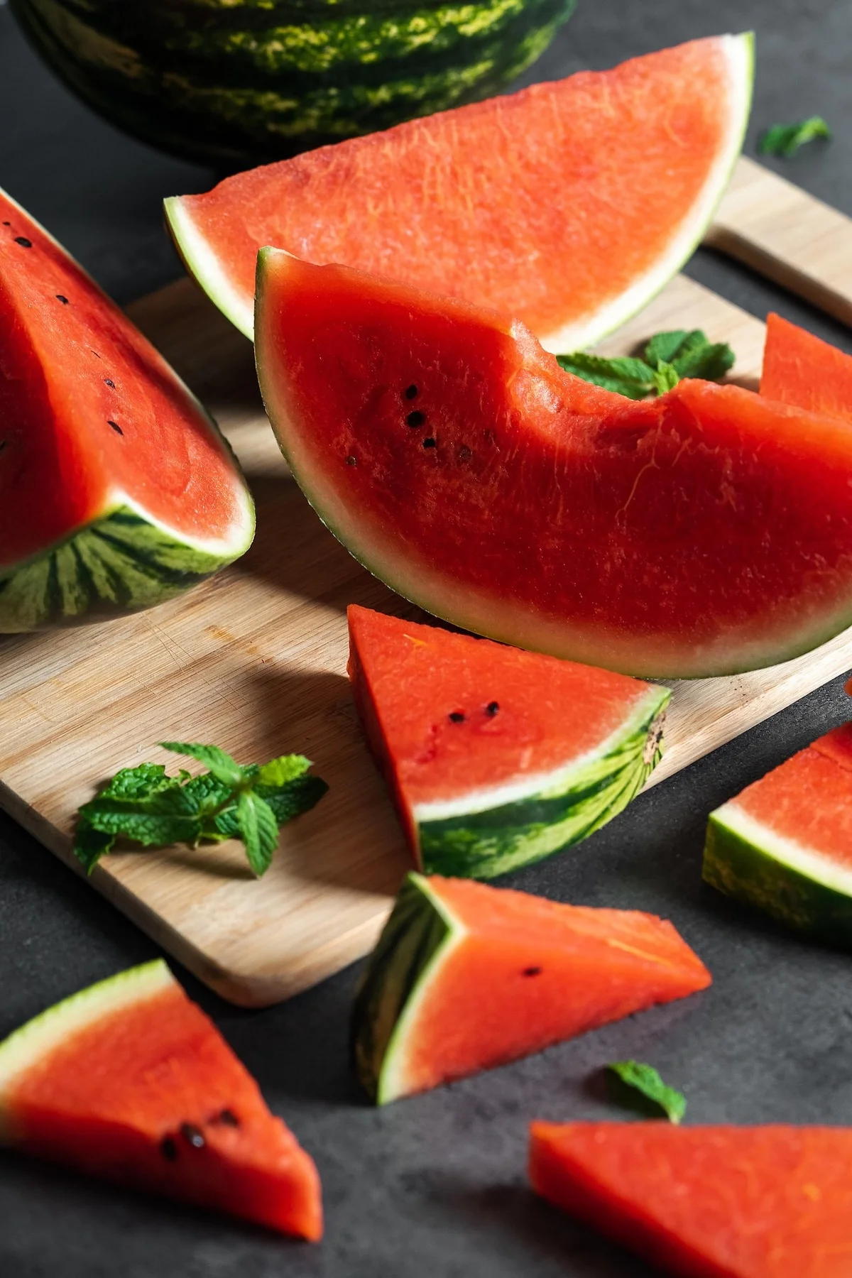 Frische Wassermelonenscheiben, garniert mit duftenden Minzblättern auf einem hölzernen Servierbrett.